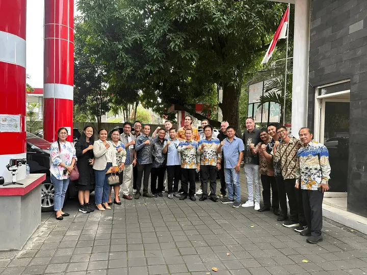 Sekelompok orang, termasuk staf ESMI, berfoto di depan gedung kantor pemerintah.